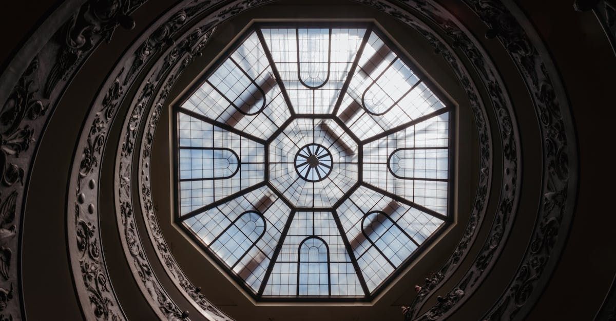 Spiral staircase looking up at an octagonal skylight, intricate architecture.