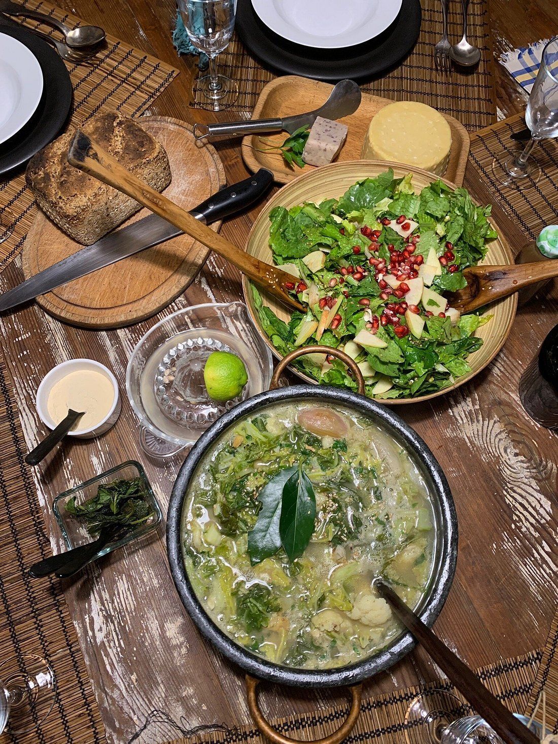 Overhead view of a dinner table set with salad, soup, bread, and other dishes.