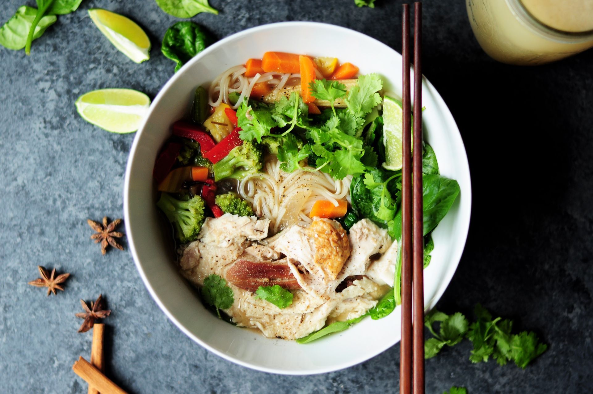 Chicken noodle soup bowl with vegetables and chopsticks.