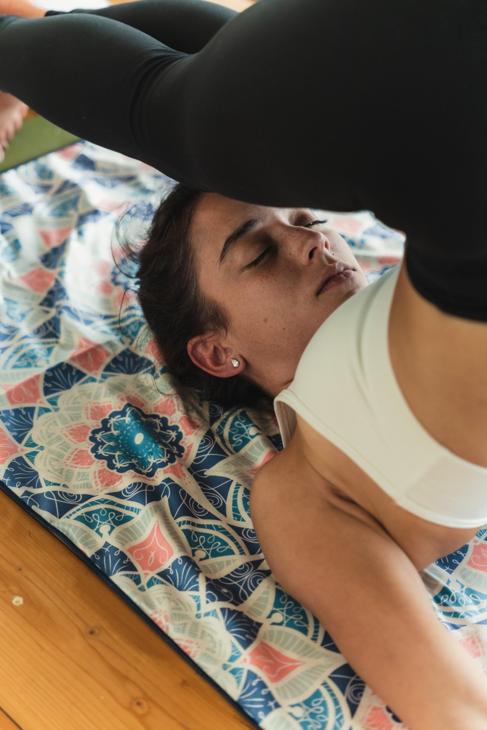 Woman in yoga pose, legs overhead, on patterned mat.