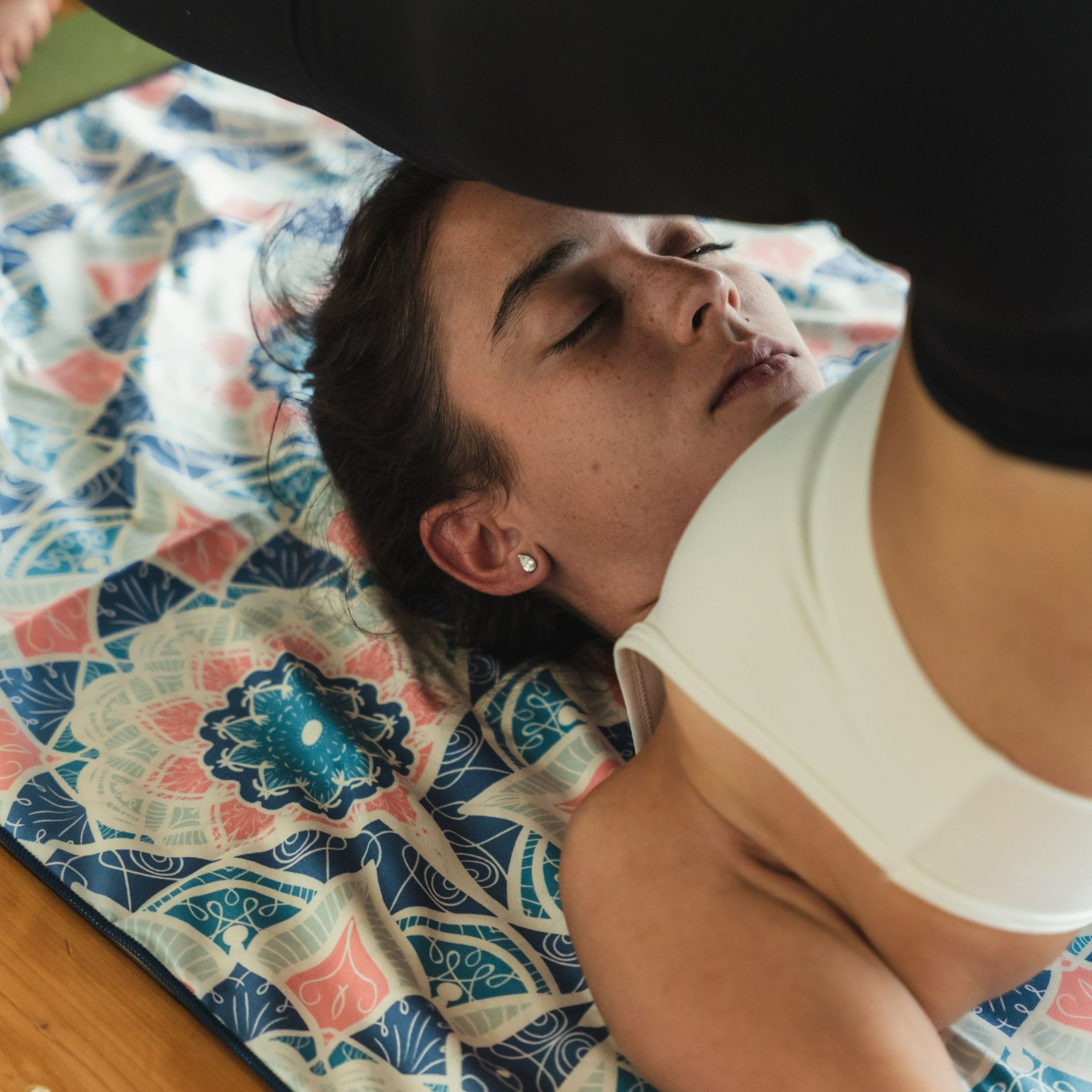 Woman in yoga pose on patterned mat, eyes closed.