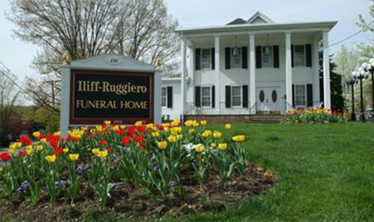 Funeral home with white columns and a flower bed of red and yellow tulips in front