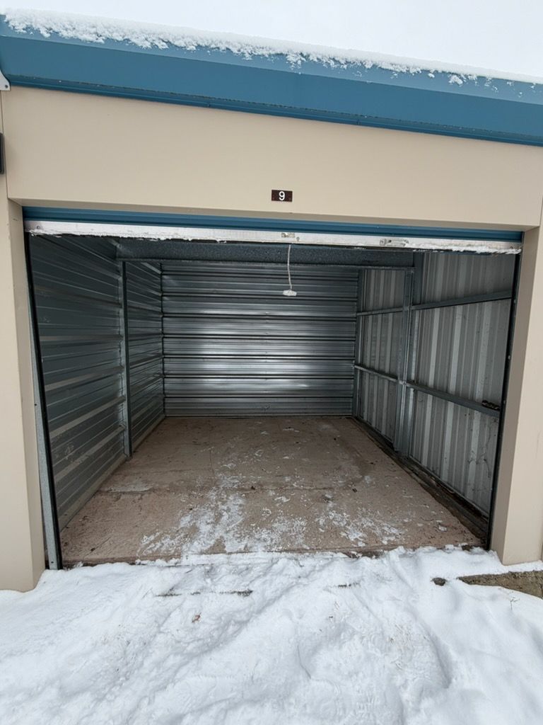 Open storage unit with snow in front.
