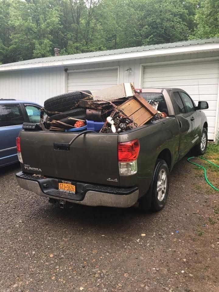 Brown Toyota pickup truck filled with debris in front of a white garage.