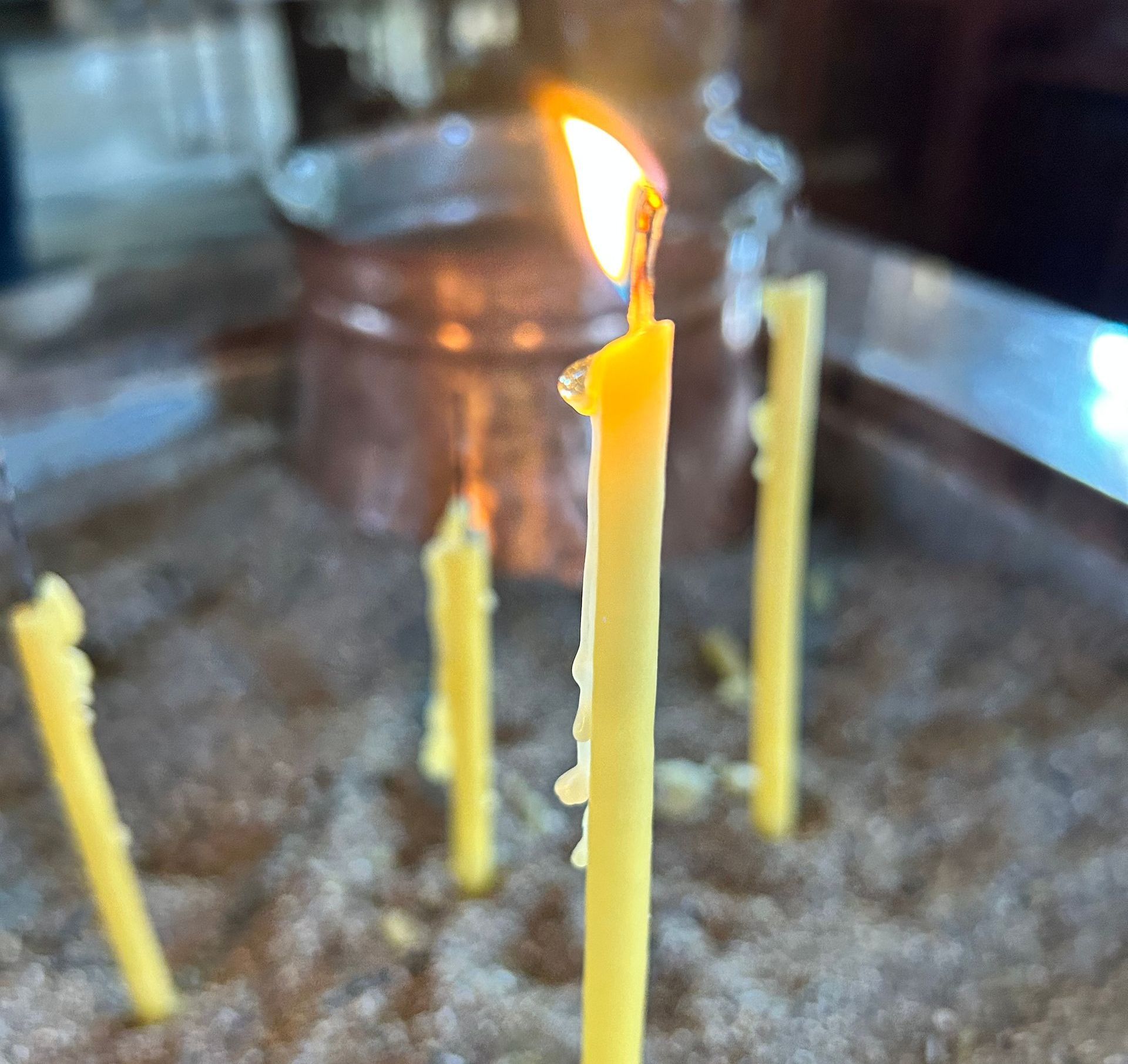 Gule lys, der brænder i en lav metalbakke, med en høj flamme i forgrunden