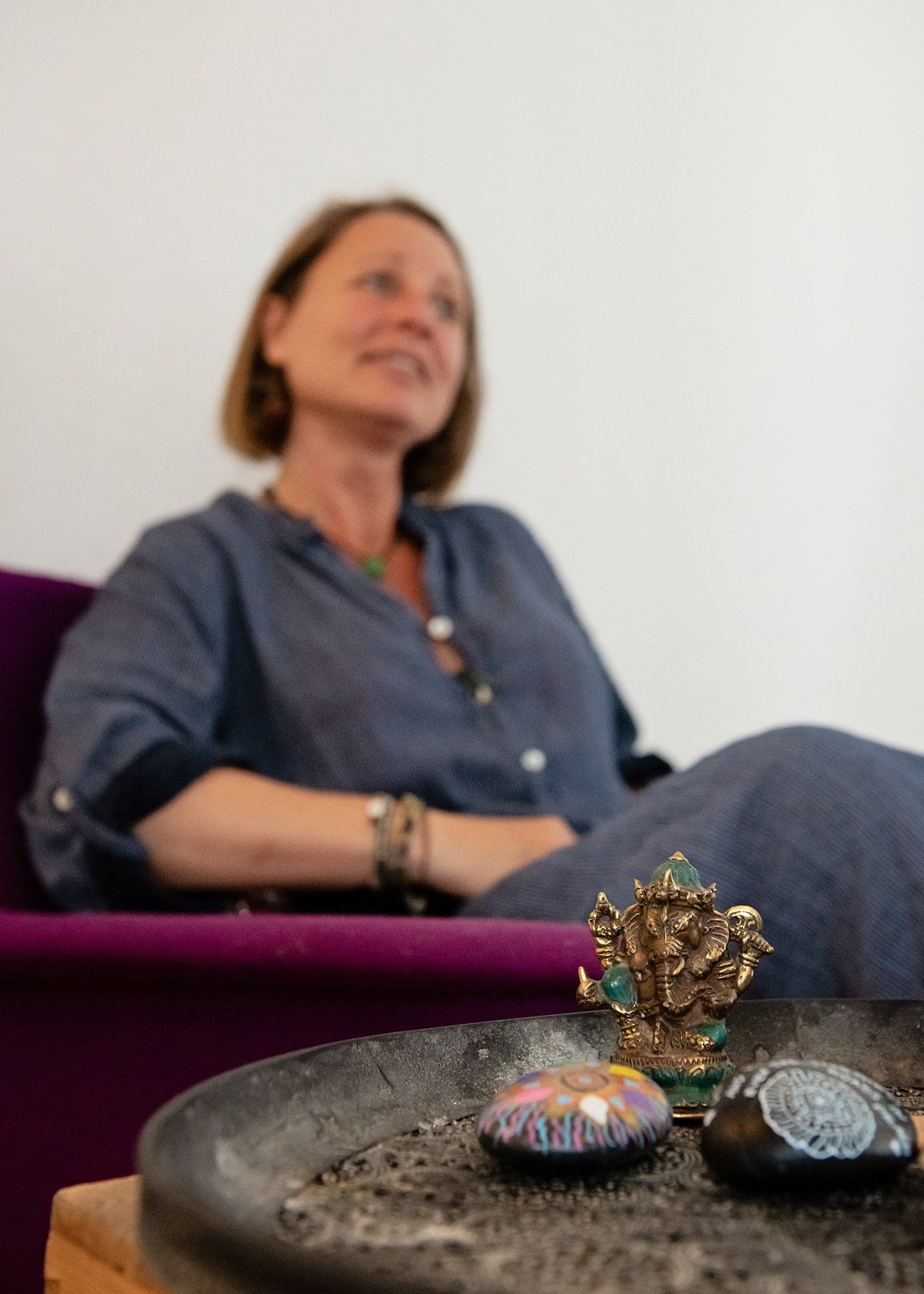 Kvinde siddende på en lilla sofa ved siden af ​​en bakke med dekorative sten og en juvelbesat ornamentik