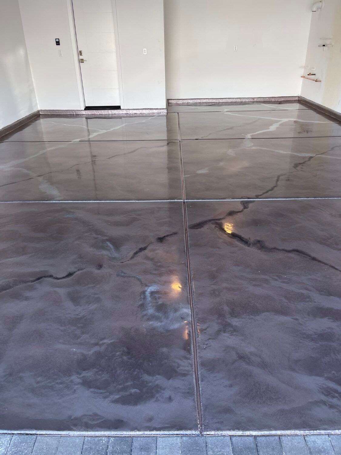 Empty room with a glossy gray tiled floor and white walls, seen from a low angle.