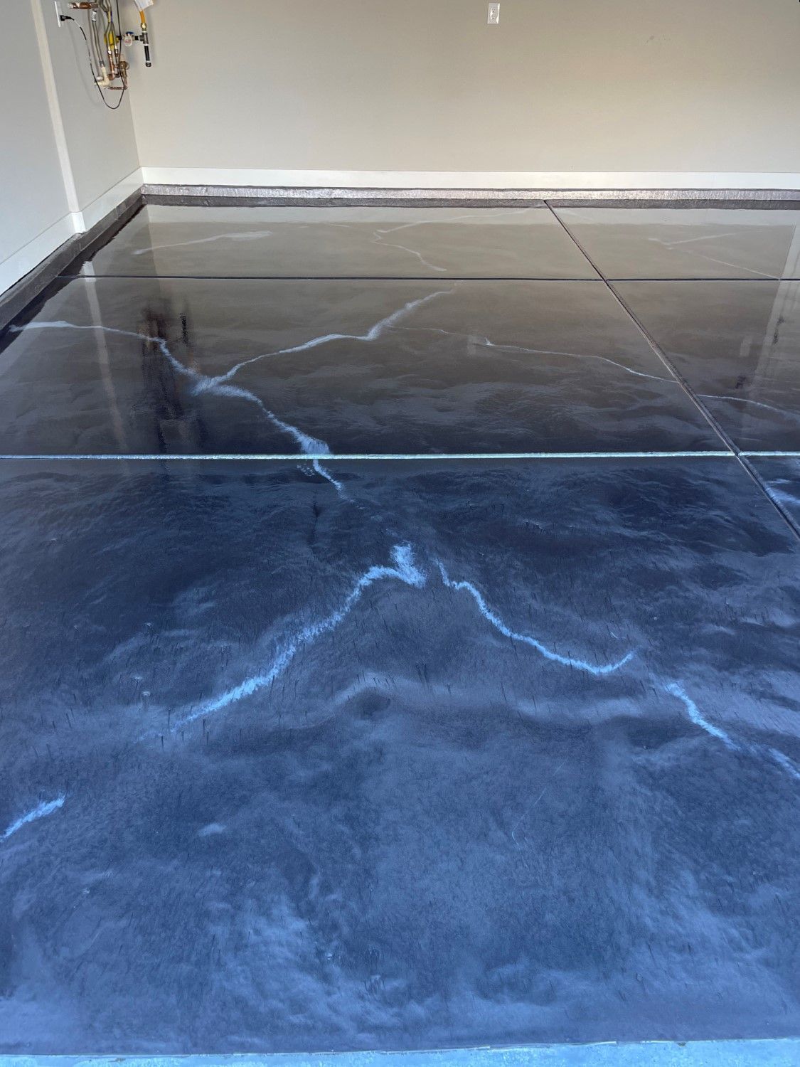 Empty room with glossy black epoxy floor and white walls, reflecting light streaks.