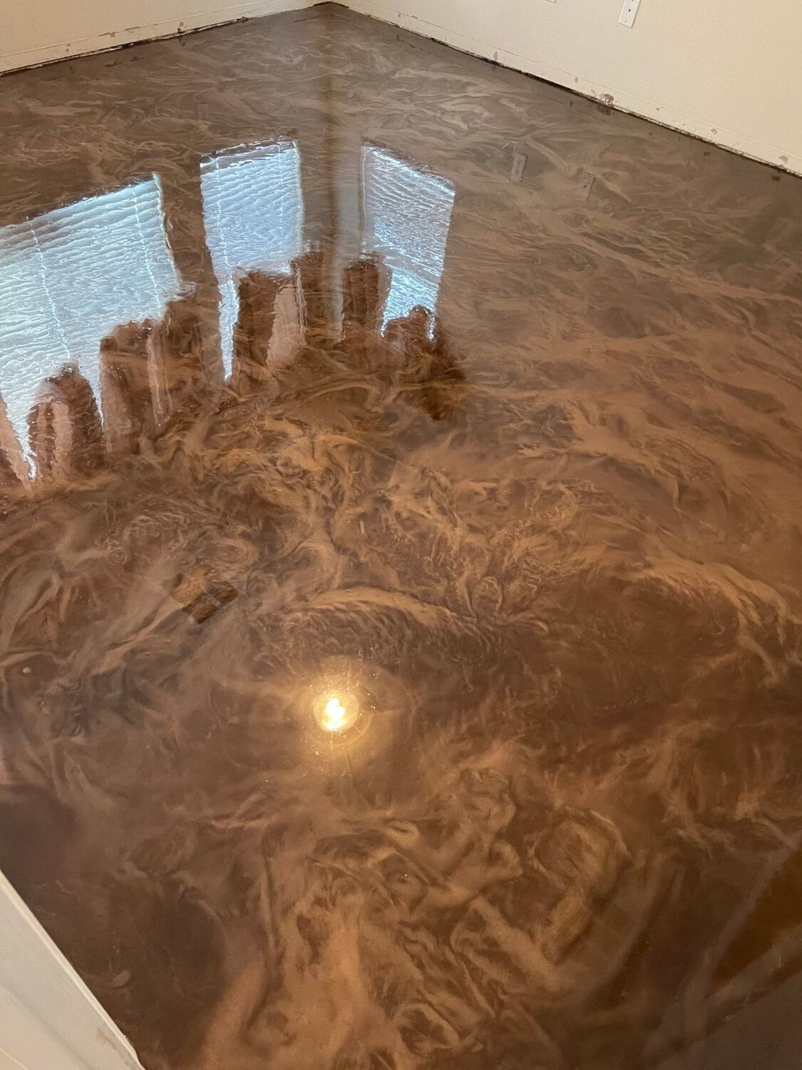 Shiny brown marble floor with light reflections and swirled patterns in an empty room