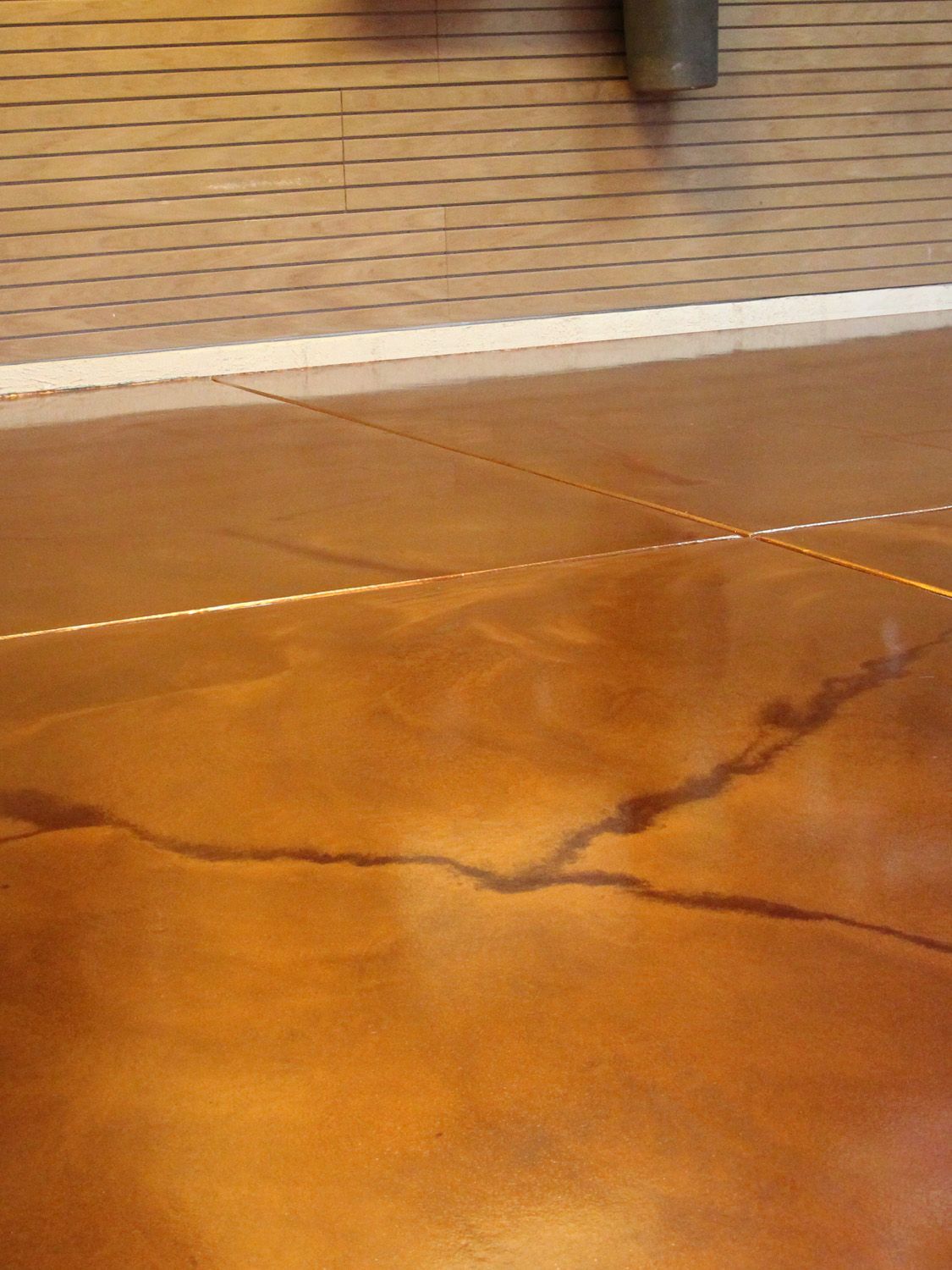 Cracked orange concrete pavement beside a brick wall and white curb line