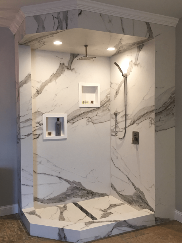 A bathroom with marble walls and a walk in shower