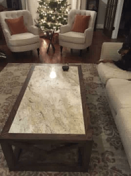 A living room with a couch , chairs , a coffee table and a christmas tree.