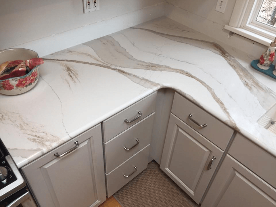 A kitchen with white cabinets and a marble counter top.
