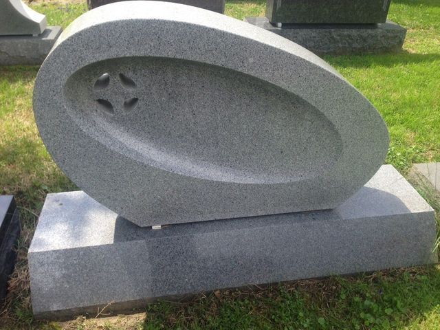 A gravestone with a star in the middle of it is sitting in the grass.