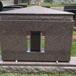 A gravestone with a vase in the middle of it in a cemetery.
