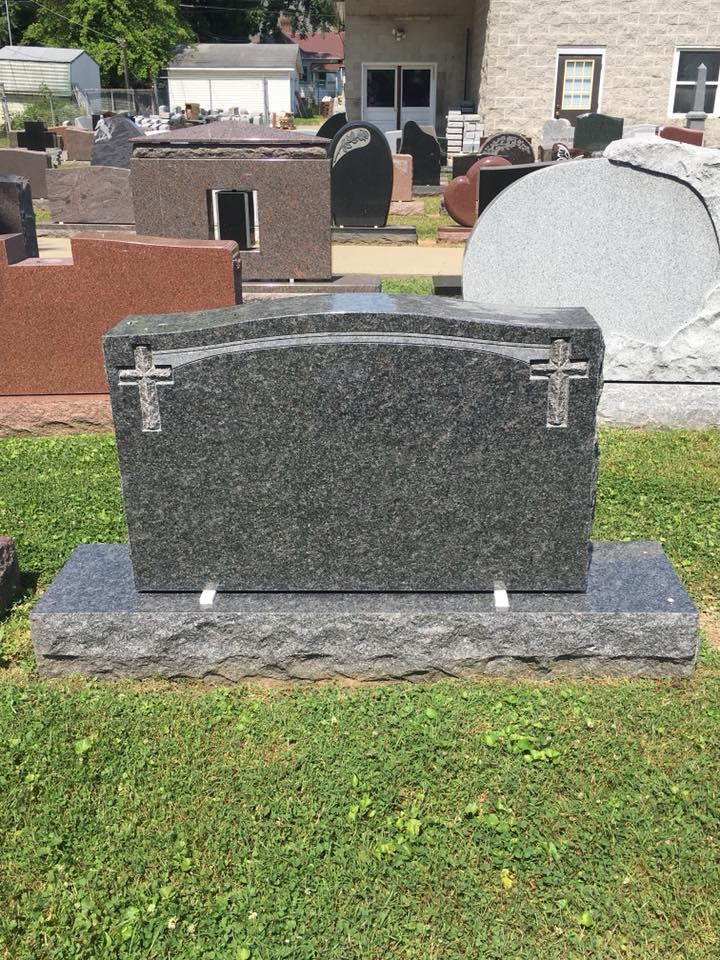 A gravestone with a cross on it is sitting in the grass.