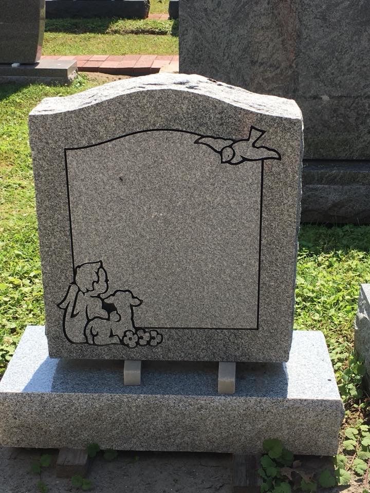 A gravestone with a picture of an angel and a dog on it