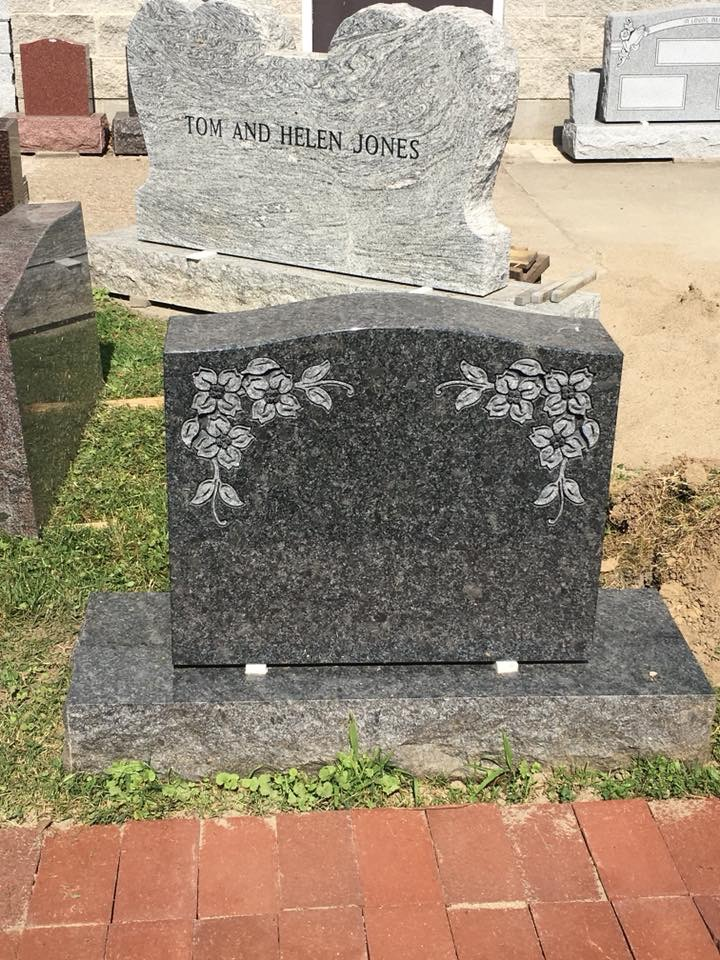 A gravestone for tom and helen jones is sitting on top of a brick walkway.