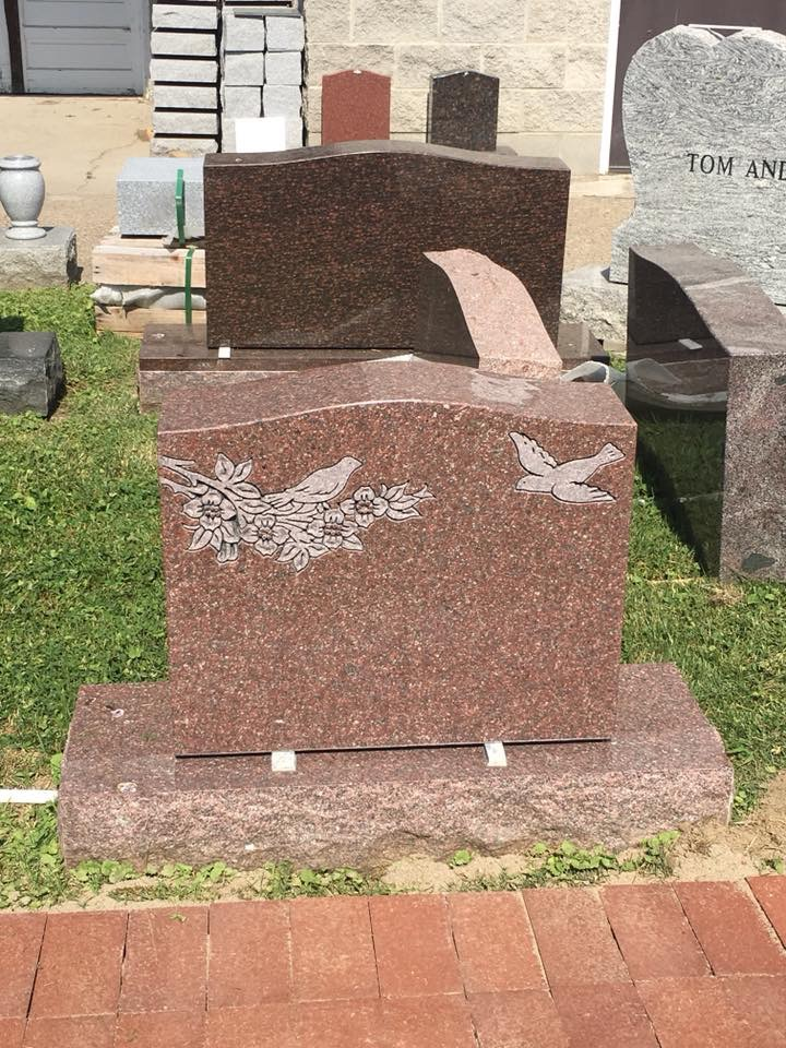 A gravestone with a bird and flowers on it