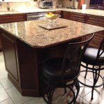 A kitchen with a large granite island and chairs.