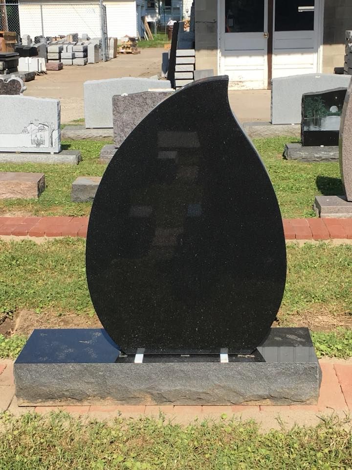 A black gravestone in the shape of a teardrop