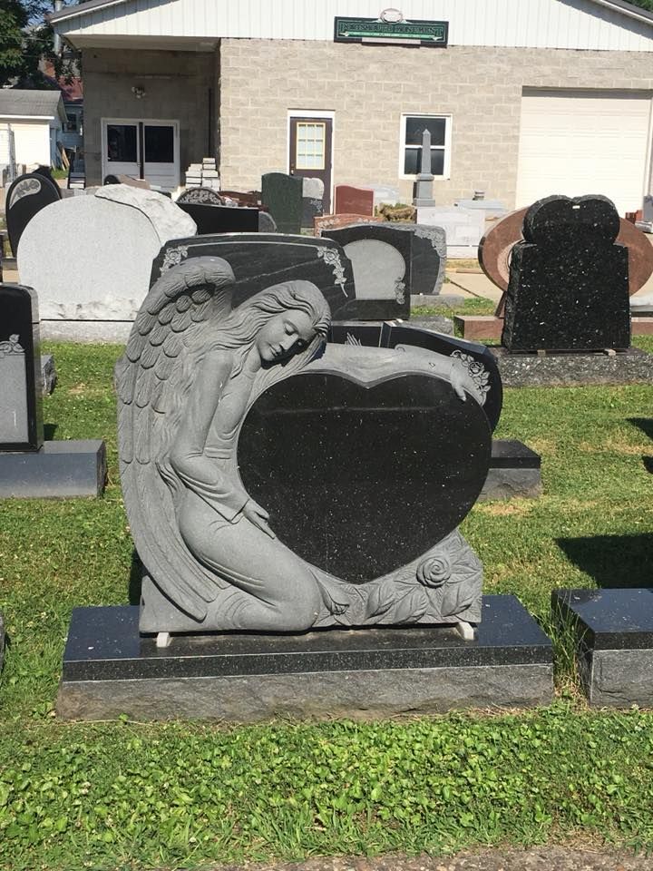 A statue of an angel holding a heart in a cemetery.