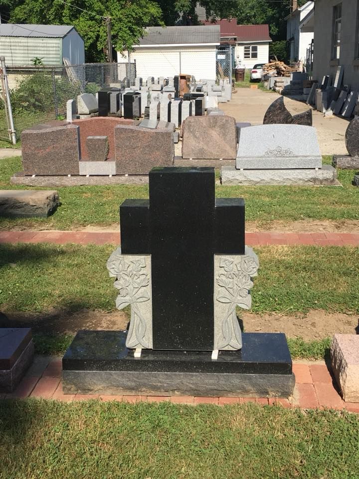 A black gravestone with a cross on it in a cemetery