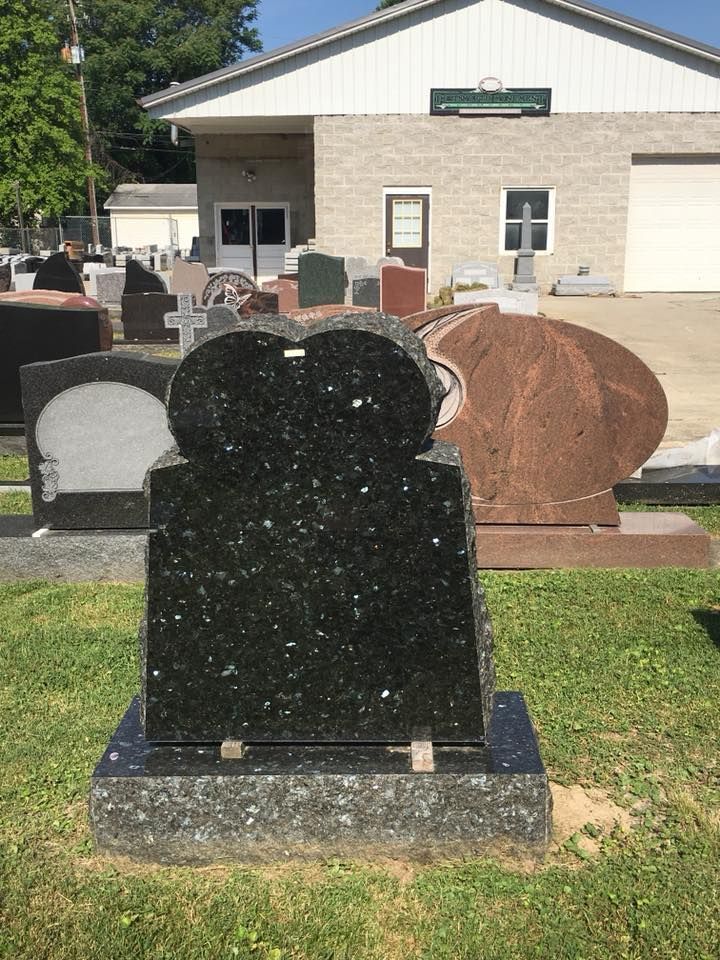 A black gravestone is sitting in the grass in front of a building.