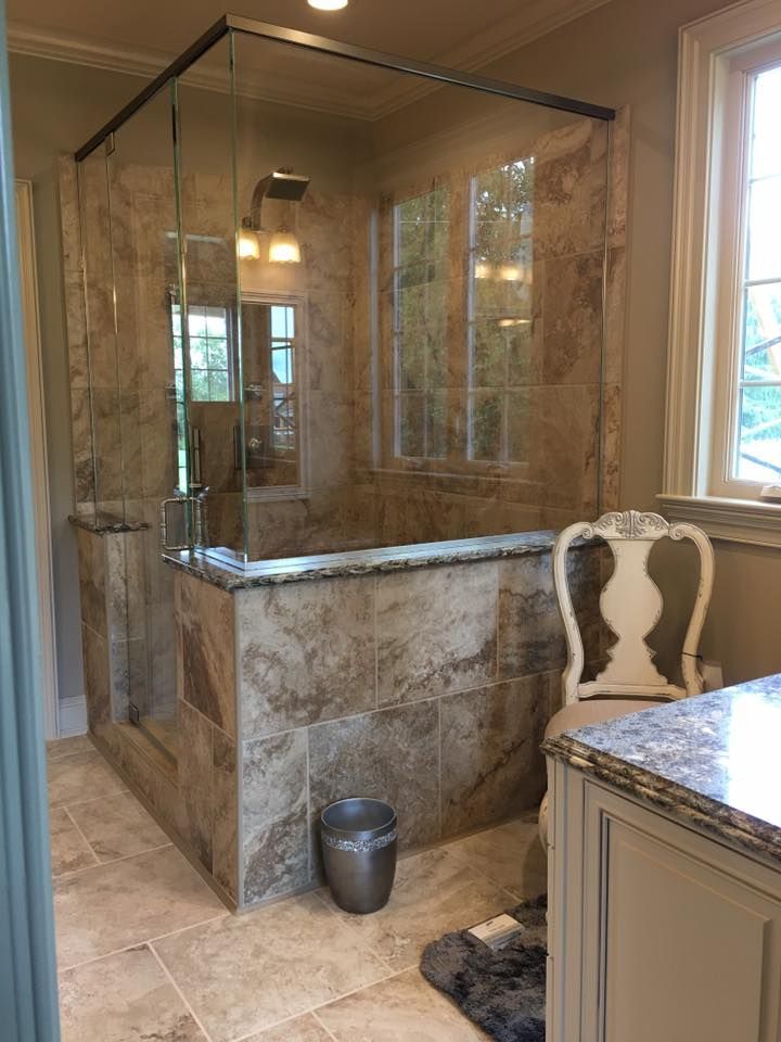 A bathroom with a walk in shower , sink , and chair.