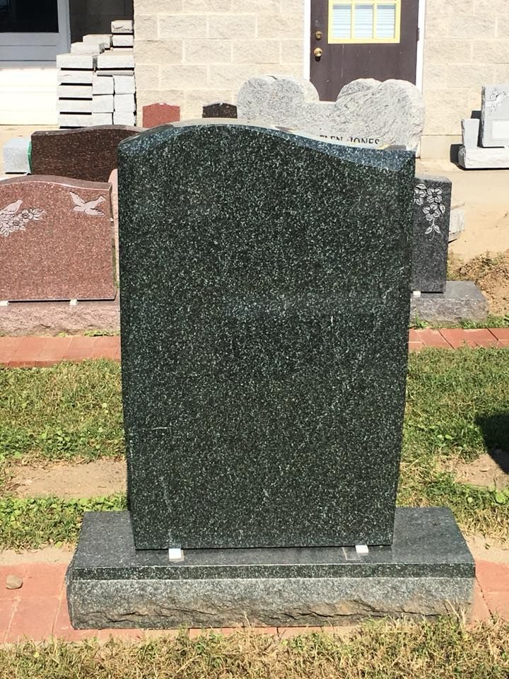 A gravestone is sitting in the grass in front of a building.