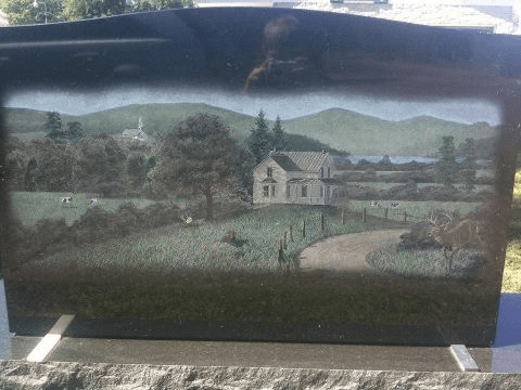 A gravestone with a picture of a house on it