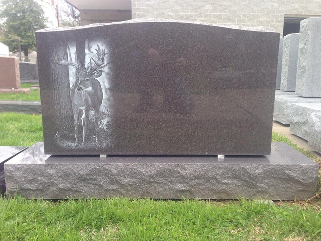 A gravestone with a picture of a deer on it