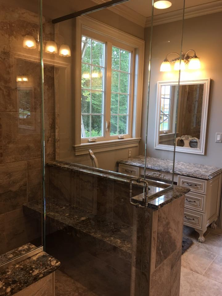A bathroom with a walk in shower , sink , mirror and window.