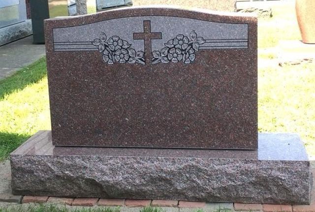 A gravestone with a cross and flowers on it