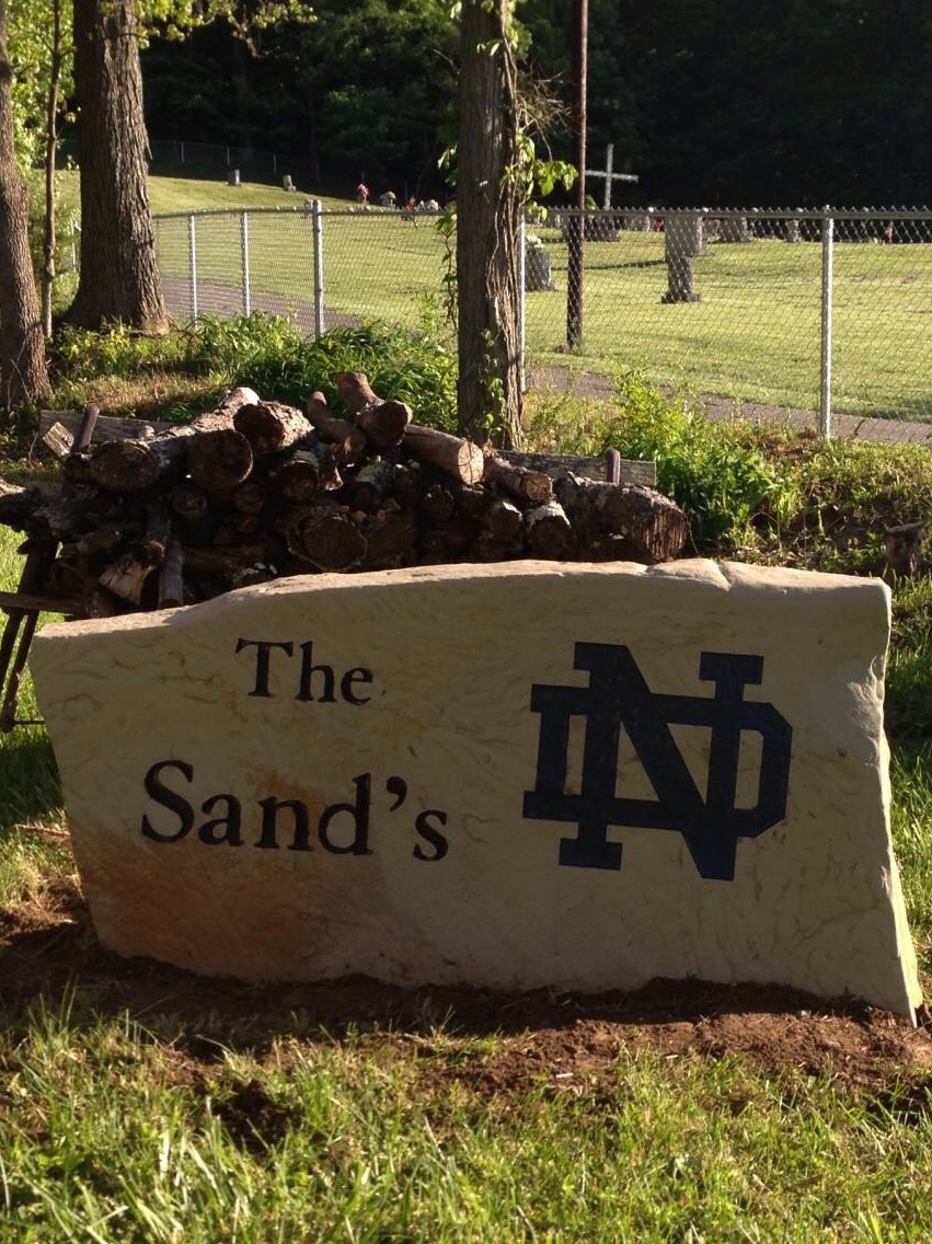 A large stone in the grass says the sand 's