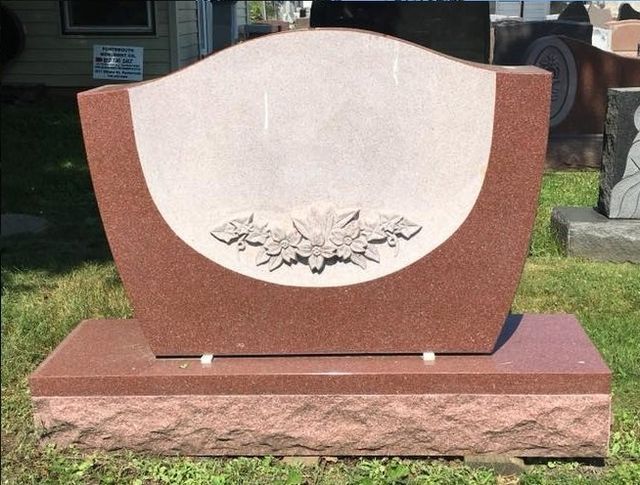 A red and white gravestone with flowers on it
