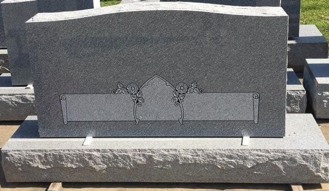 A gray gravestone with a floral design on it