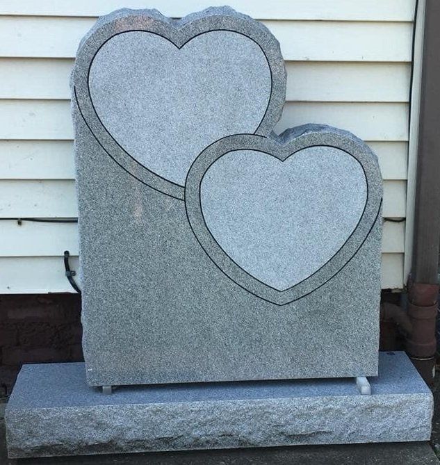 A gravestone with two hearts carved into it