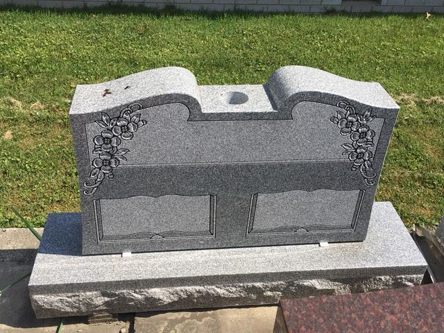 A gravestone is sitting on top of a grave in a cemetery.