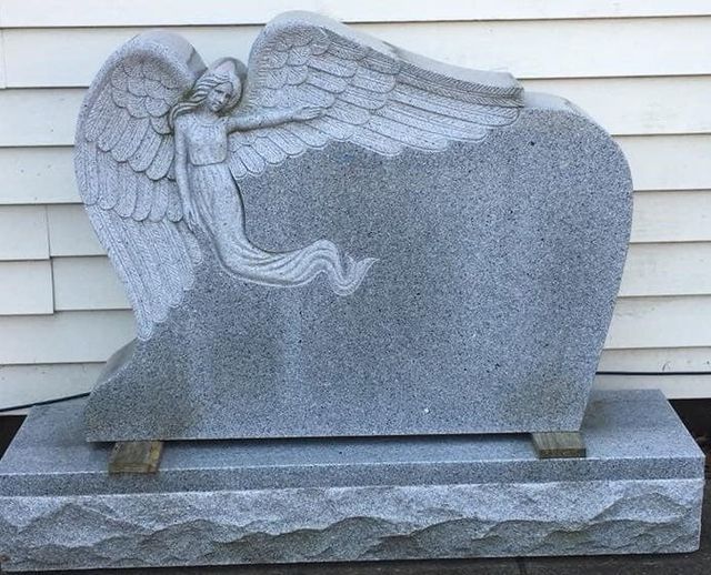 A gravestone with a statue of an angel on it