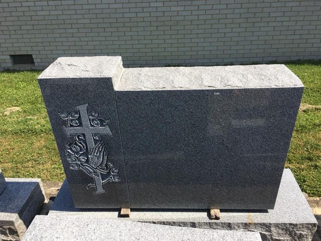 A gravestone with a cross and a tree carved into it