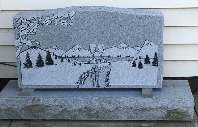A gravestone with a picture of mountains and trees on it
