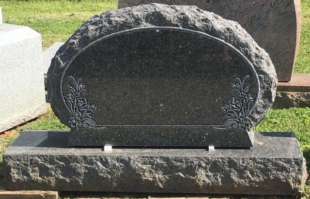 A black gravestone with a floral design on it