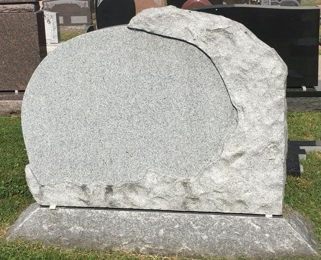 A gravestone in a cemetery that looks like a rock