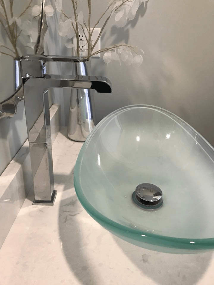A bathroom sink with a faucet and a vase of flowers on the counter.