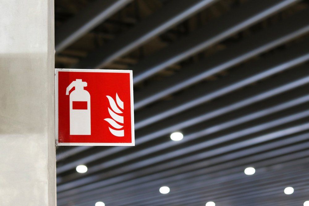 Red Fire Extinguisher Sign on a White Column — Hunter Fire & Safety in Lake Macquarie, NSW
