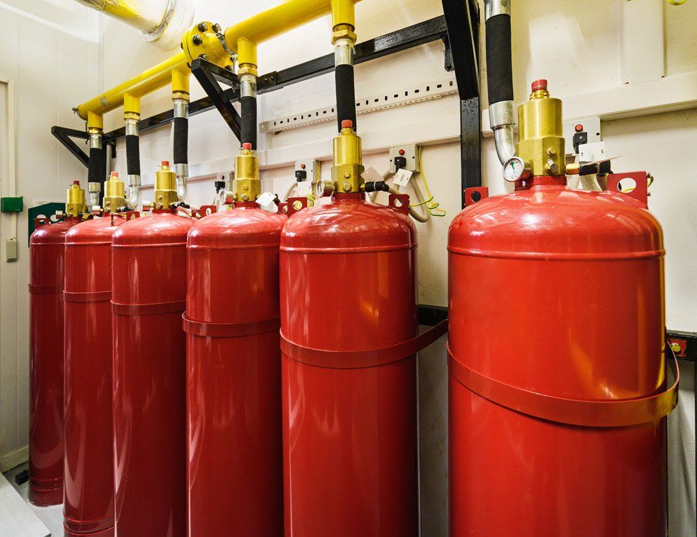 Red Fire Suppression Cylinders Mounted in a Room With Yellow and Black Pipes — Hunter Fire & Safety in Edgeworth, NSW