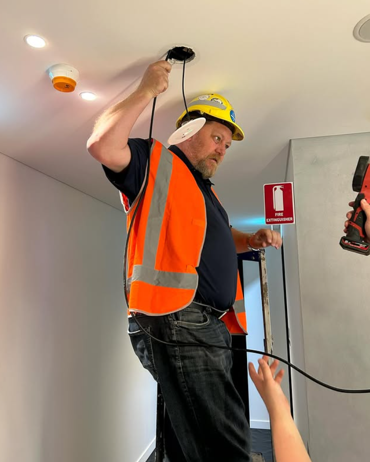 Man in Safety Vest, Hard Hat Working on Ceiling Wiring — Hunter Fire & Safety in Edgeworth, NSW