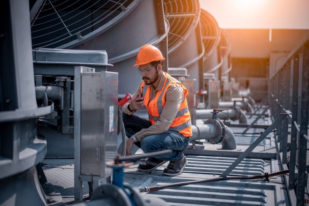 an Engineer in Safety Gear Inspects Hvac Equipment on a Rooftop — Hunter Fire & Safety in Port Stephens, NSW
