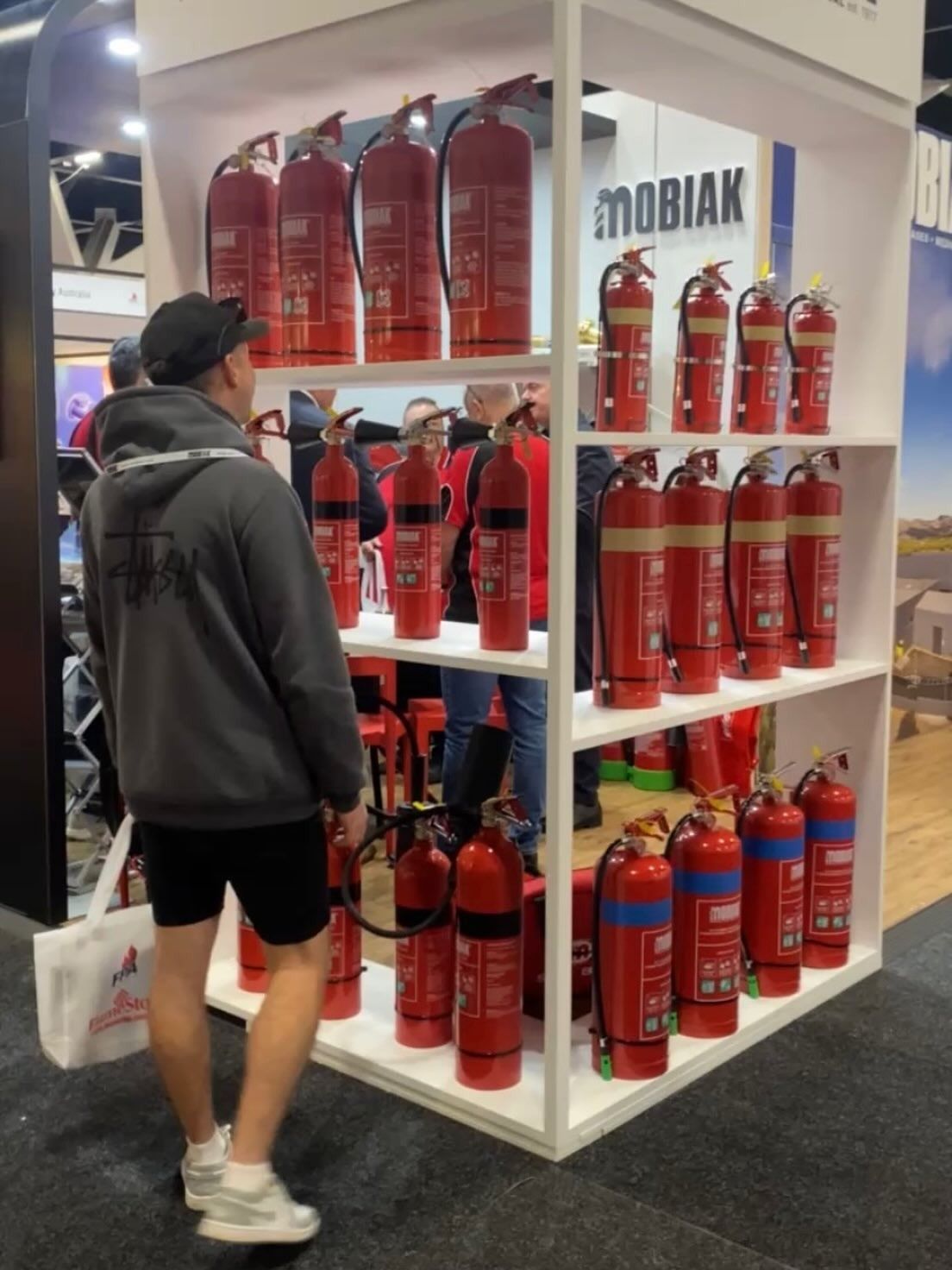 A Person Looking at a Display of Red Fire Extinguishers on Shelves — Hunter Fire & Safety in Edgeworth, NSW